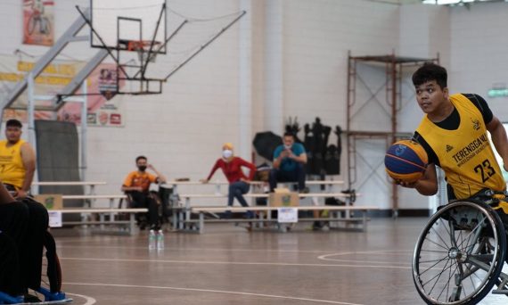 Dynamic wheelchair basketball game showcasing skill and determination indoors.